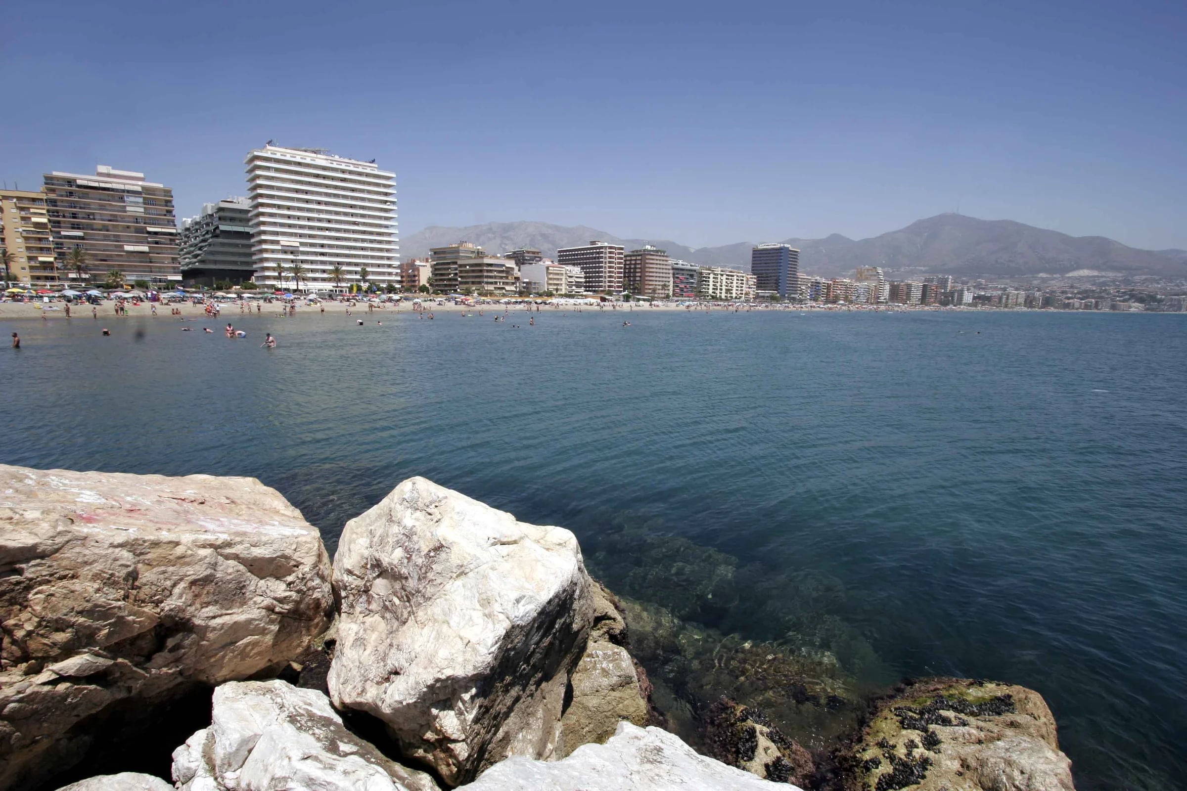 Playa de Fuengirola desde las rocas, con los edificios del paseo marítimo y la sierra al fondo