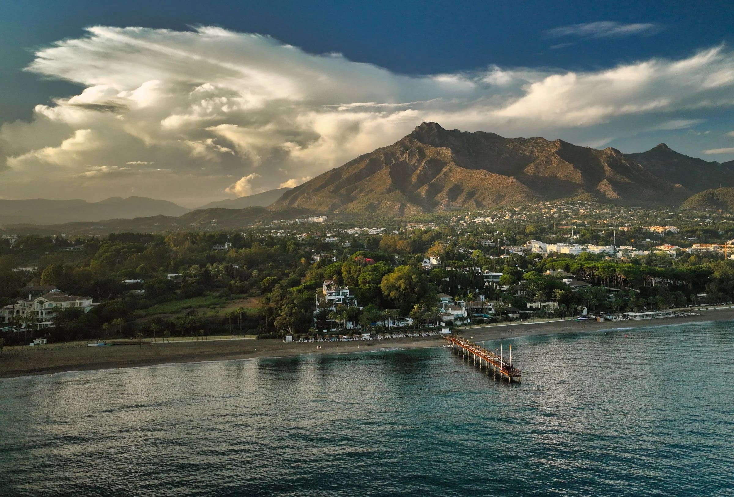 Costa de Marbella con el pantalán, la playa y La Concha bajo un cielo de tormenta