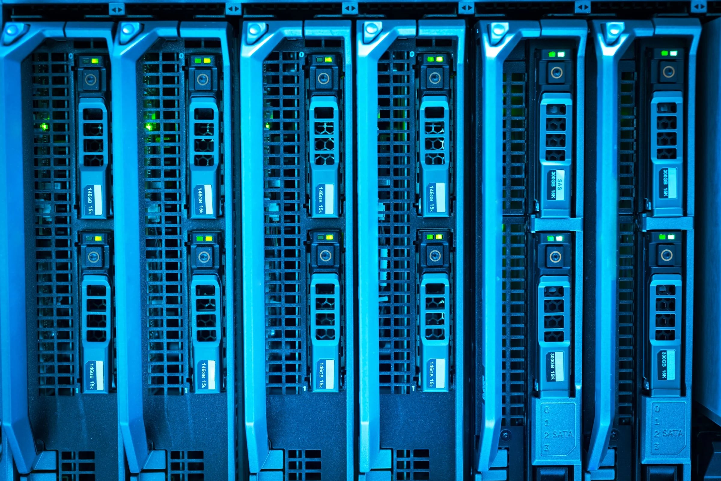 Bahías de discos de varios servidores en rack con luces de actividad verdes y luz azulada