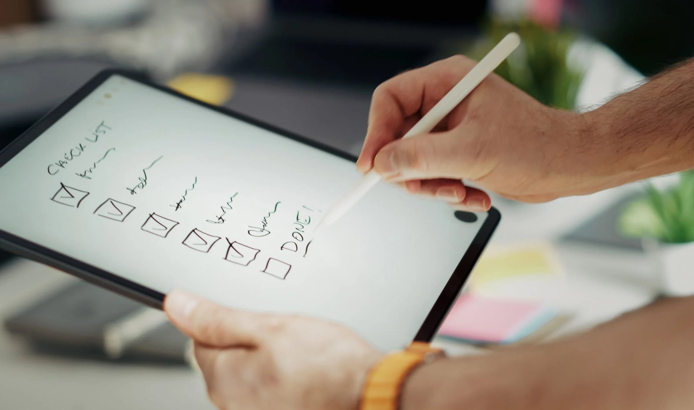 Manos marcando una lista de comprobación manuscrita en una tableta con lápiz digital