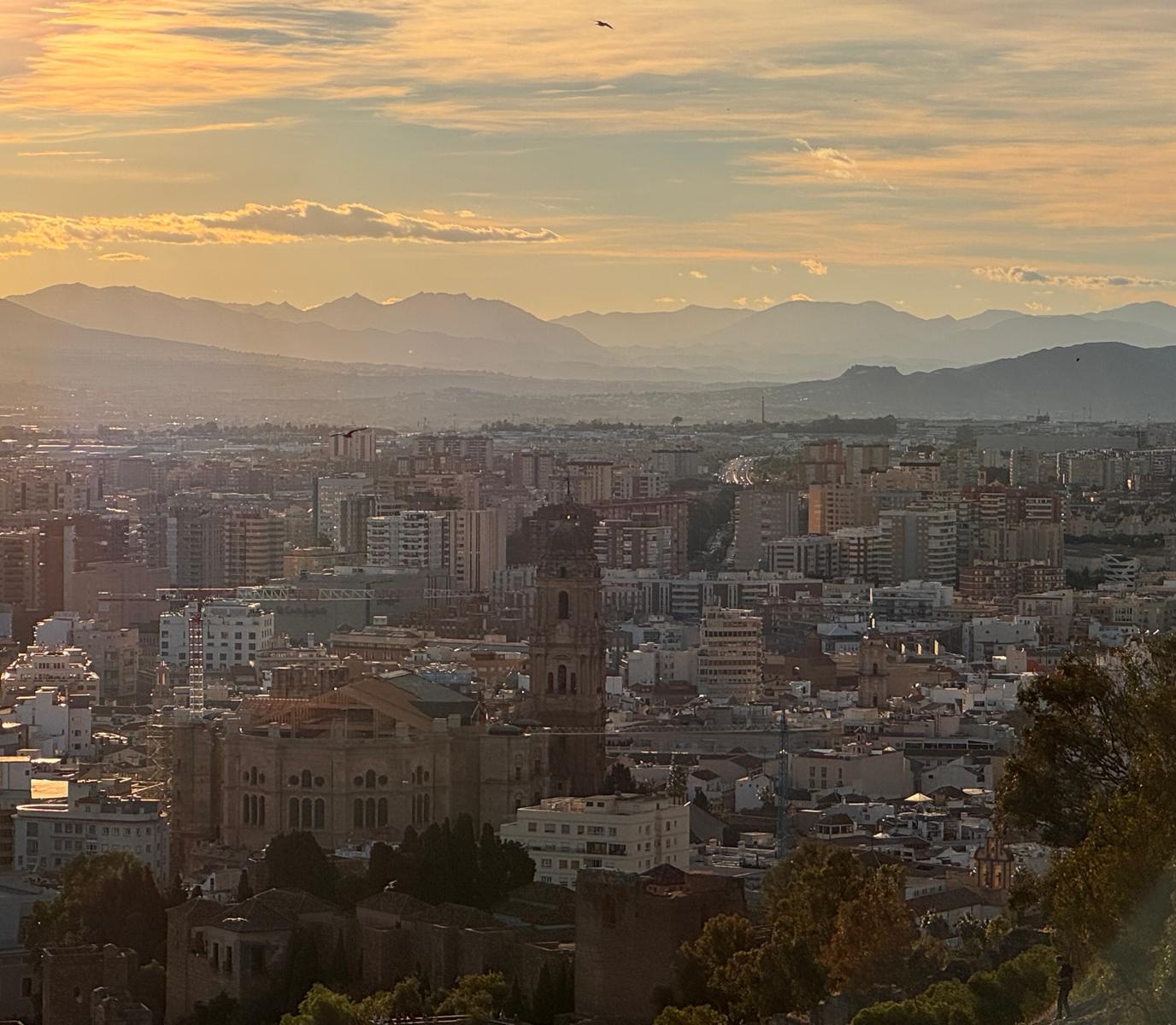 La catedral de Málaga y los tejados del centro al atardecer, con los montes al fondo