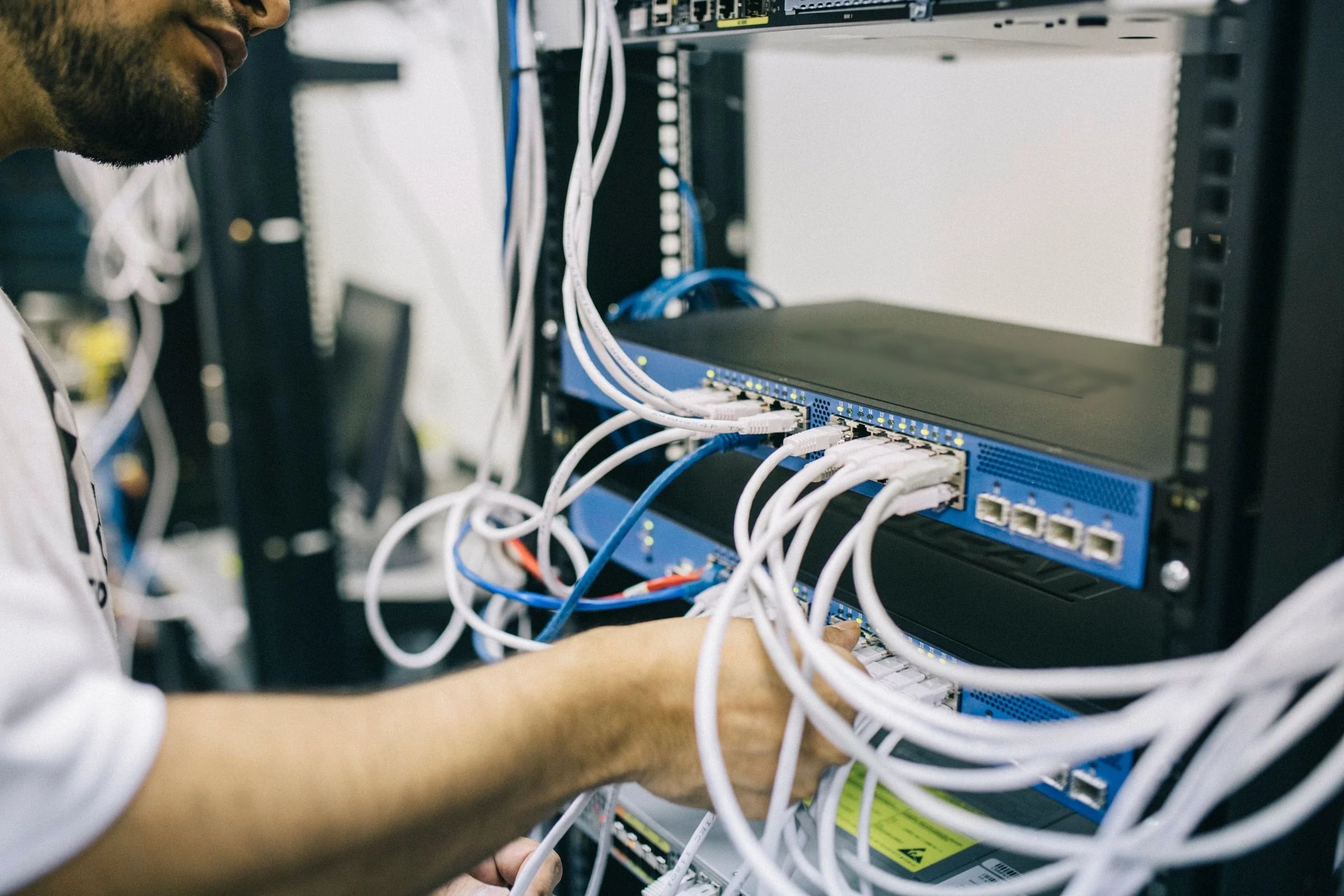 Técnico conectando cables de red a un appliance azul con luces LED montado en un rack