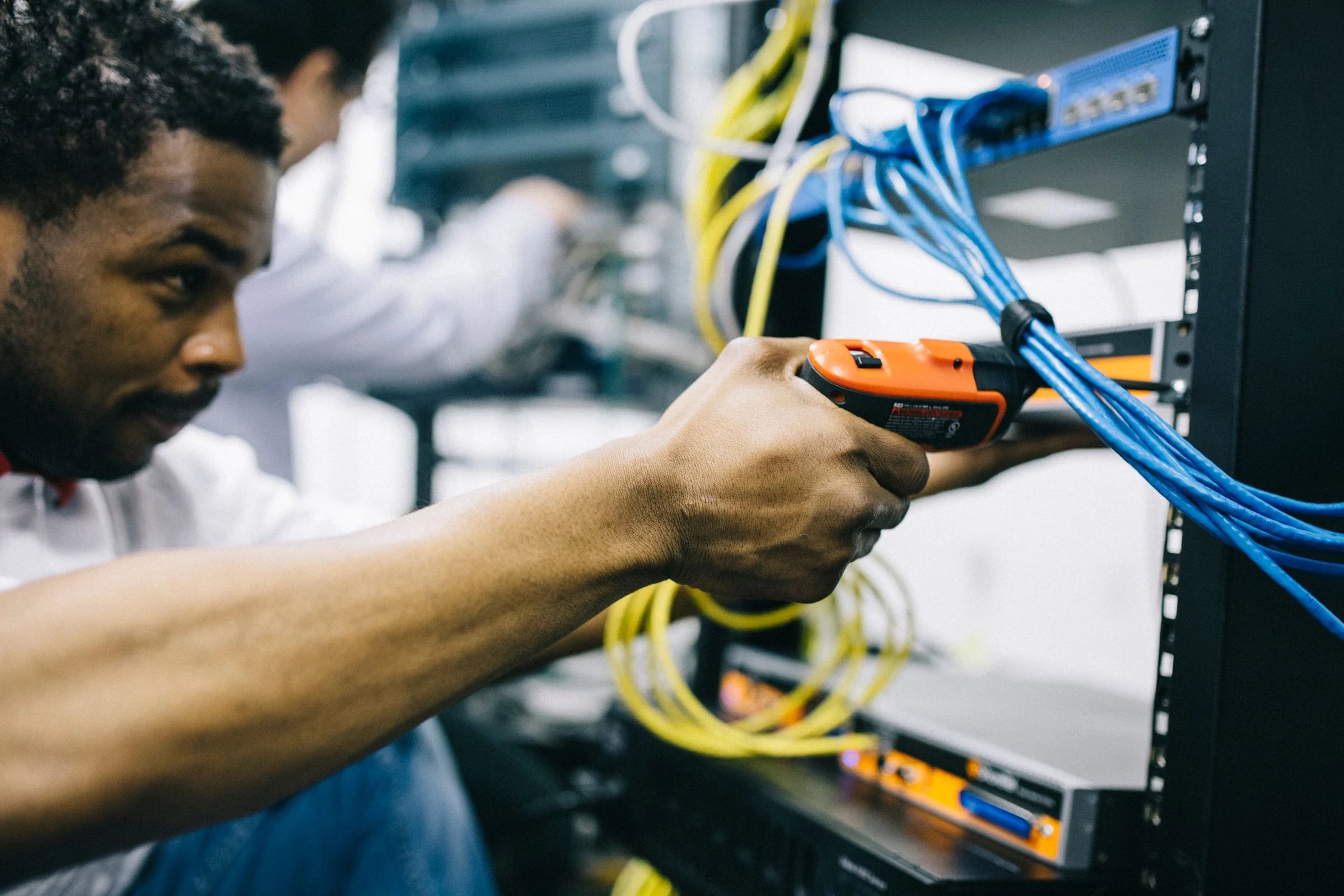 Técnico usando un comprobador de cables en los latiguillos azules de un armario rack